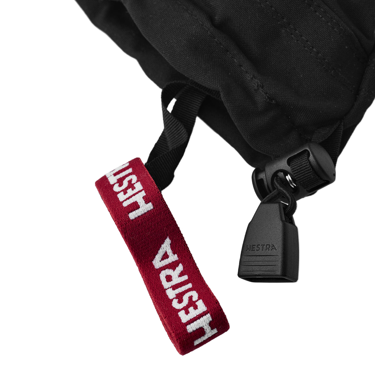 Black backpack with red strap featuring 'HESTRA' branding on a white background