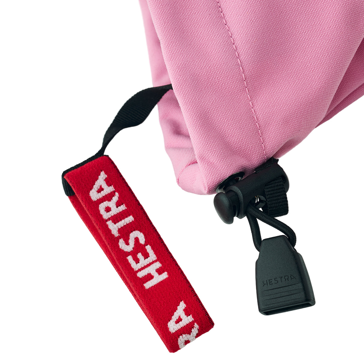 Red strap with 'HESTRA' branding on a pink jacket against a white background