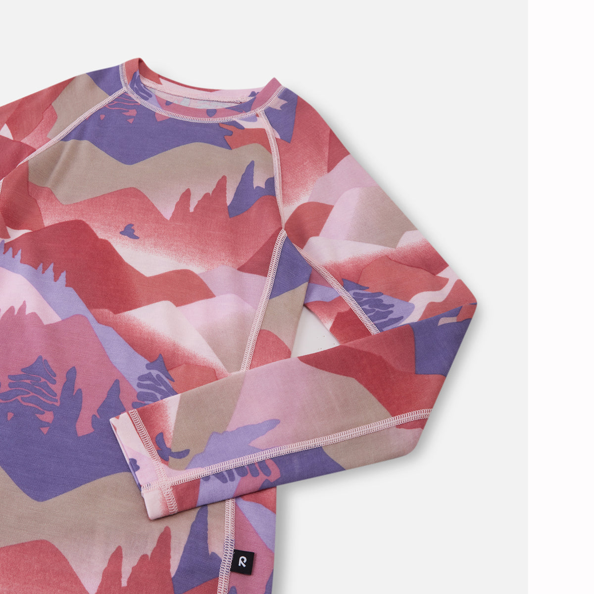 A long-sleeve crewneck shirt with a colorful abstract mountain pattern in pink, red, purple, and beige, shown on a light gray background.