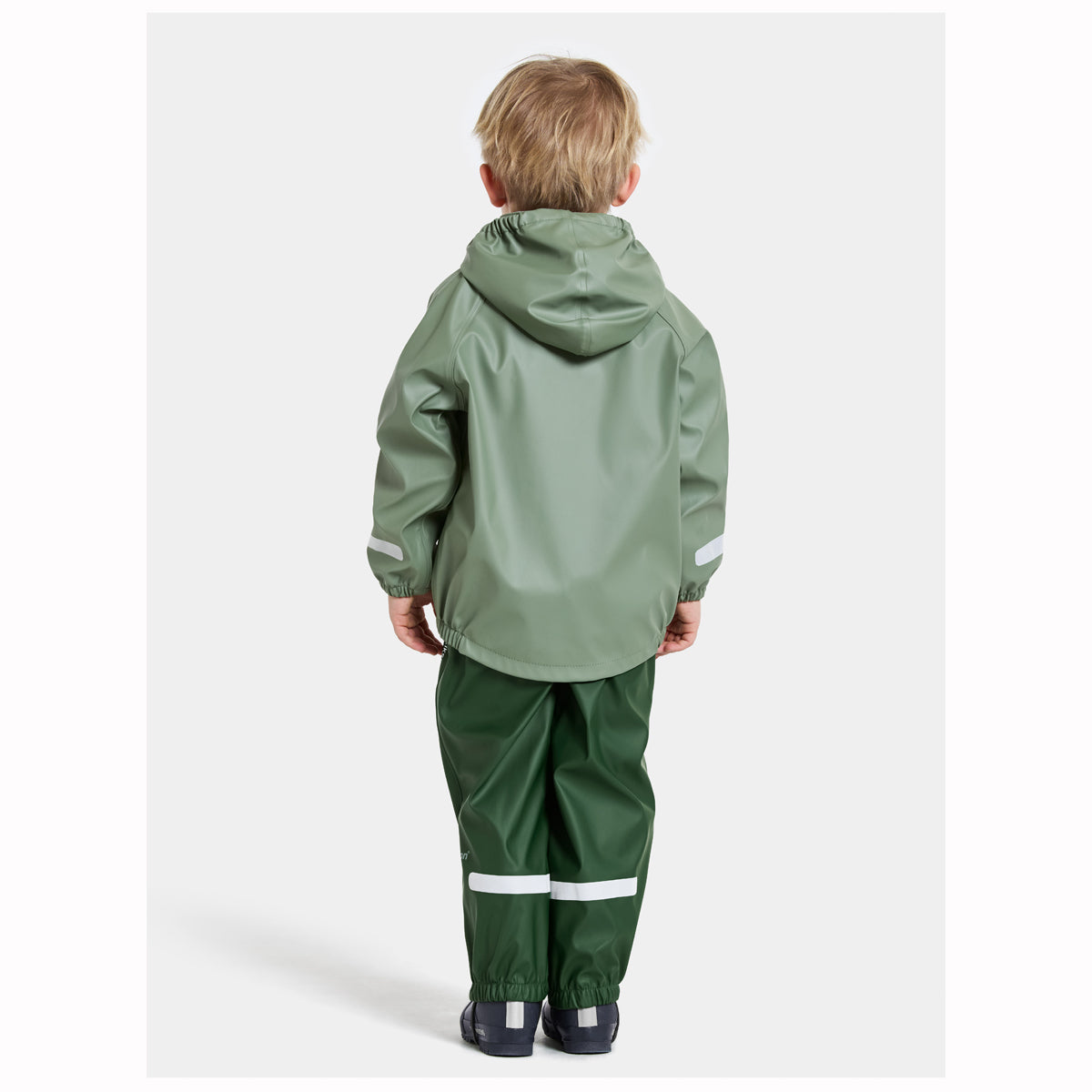 Child wearing a green raincoat and pants on a white background