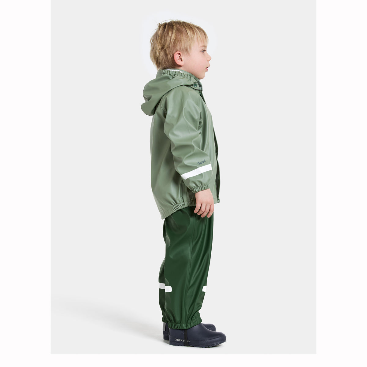 Child wearing a green raincoat and pants with reflective stripes on a white background