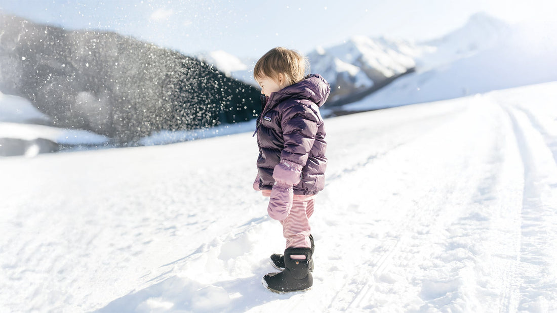Todder in snow wearig winter boots and jacket