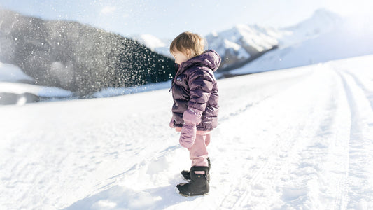Todder in snow wearig winter boots and jacket