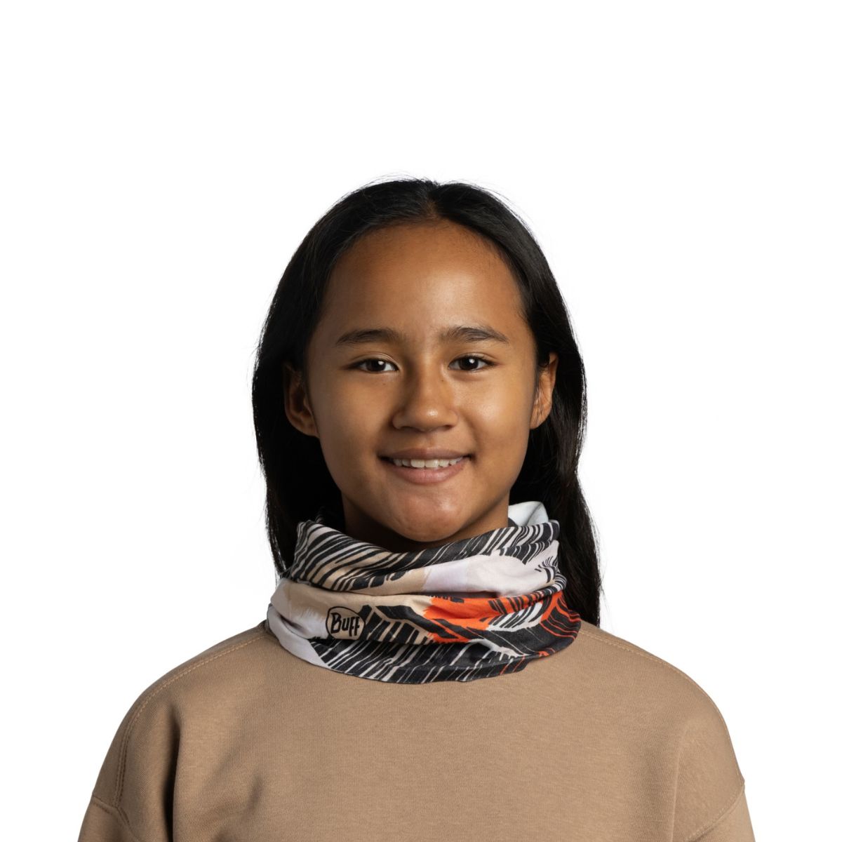 A young girl with long dark hair smiling, wearing a patterned neck gaiter with black, white, and orange accents, and a beige sweatshirt against a plain white background.