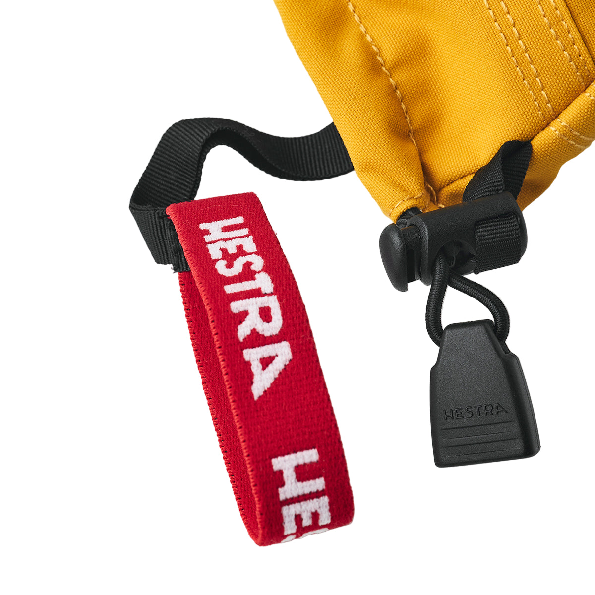 Close-up of a red Hestra strap attached to a yellow jacket on a white background
