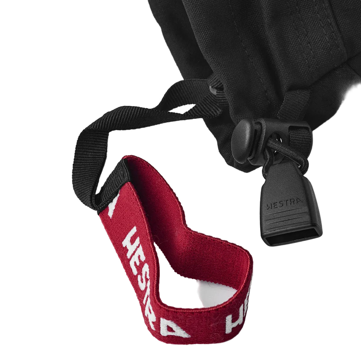 Close-up of a black strap with a red Hestra label on a white background