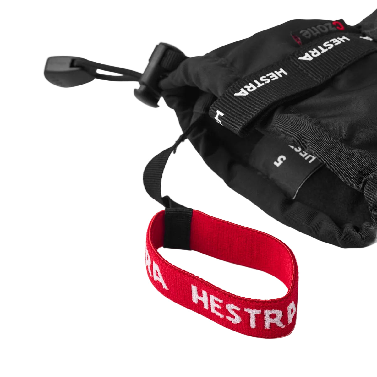 Black gloves with a red Hestra strap on a light gray background