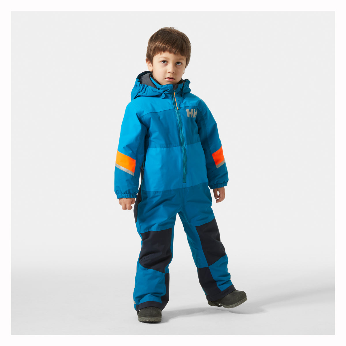 Child wearing a blue snowsuit with orange accents on a white background