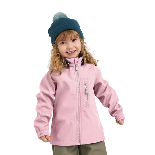 A young girl smiling and wearing a light pink children's zip-up jacket, a dark teal knit beanie with a pom-pom, and olive green pants, photographed against a neutral light gray studio background.