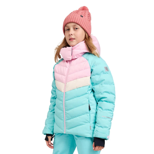 A young girl wearing a light blue and pink color-blocked puffer jacket, matching light blue ski pants, and a pink knit beanie, photographed against a neutral light gray studio background.