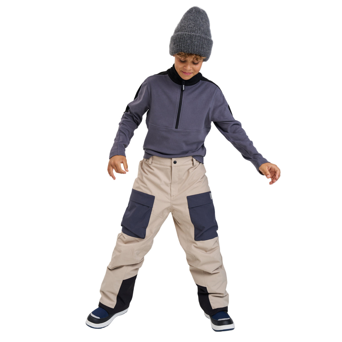Boy wearing bobble hat, fleece jumper and beige ski pants on white background