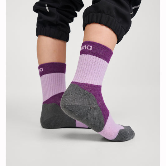 Purple and gray socks with brand logo worn by a child on a light gray background