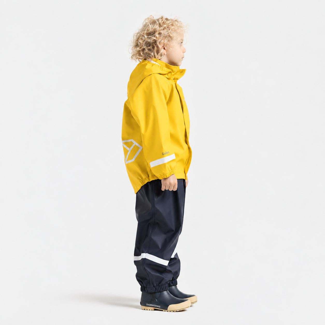 A child model shown in profile wearing a bright yellow hooded rain jacket with reflective white stripes and dark navy pants, standing against a clean white studio background.
