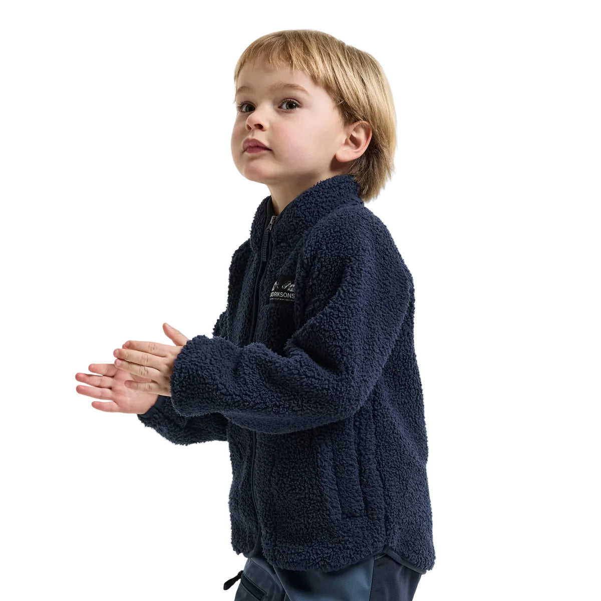 A young boy wearing a navy blue sherpa fleece zip-up jacket, standing against a light gray studio background.