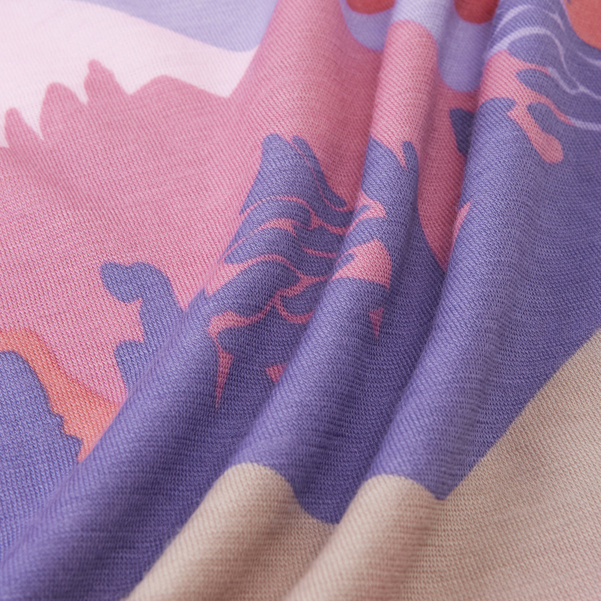 A close-up of draped fabric with a soft abstract landscape print in lavender purple, pink, peach, and beige tones.