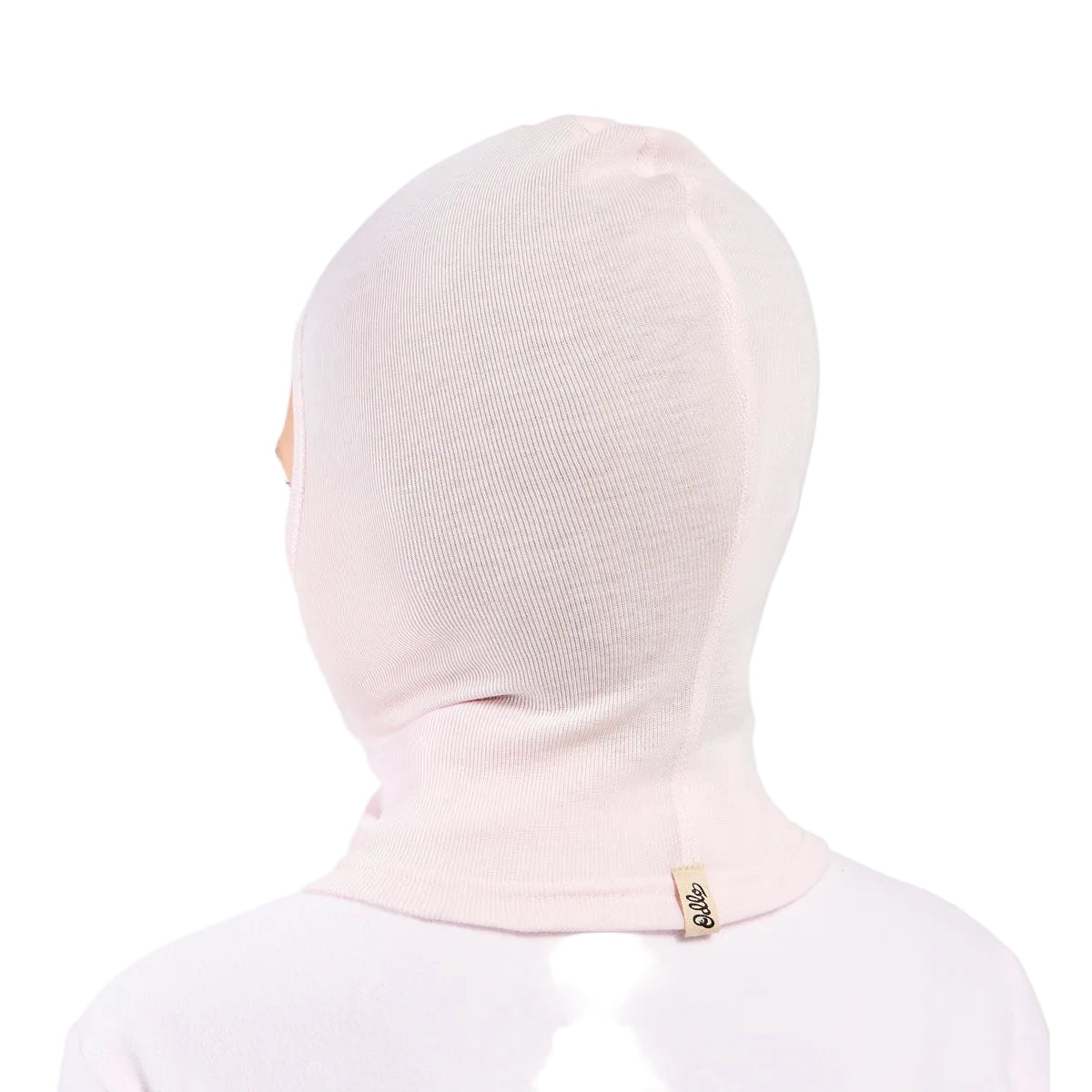 A light pink knit balaclava hood shown from the back on a model, featuring a small beige brand tag on the back neck.