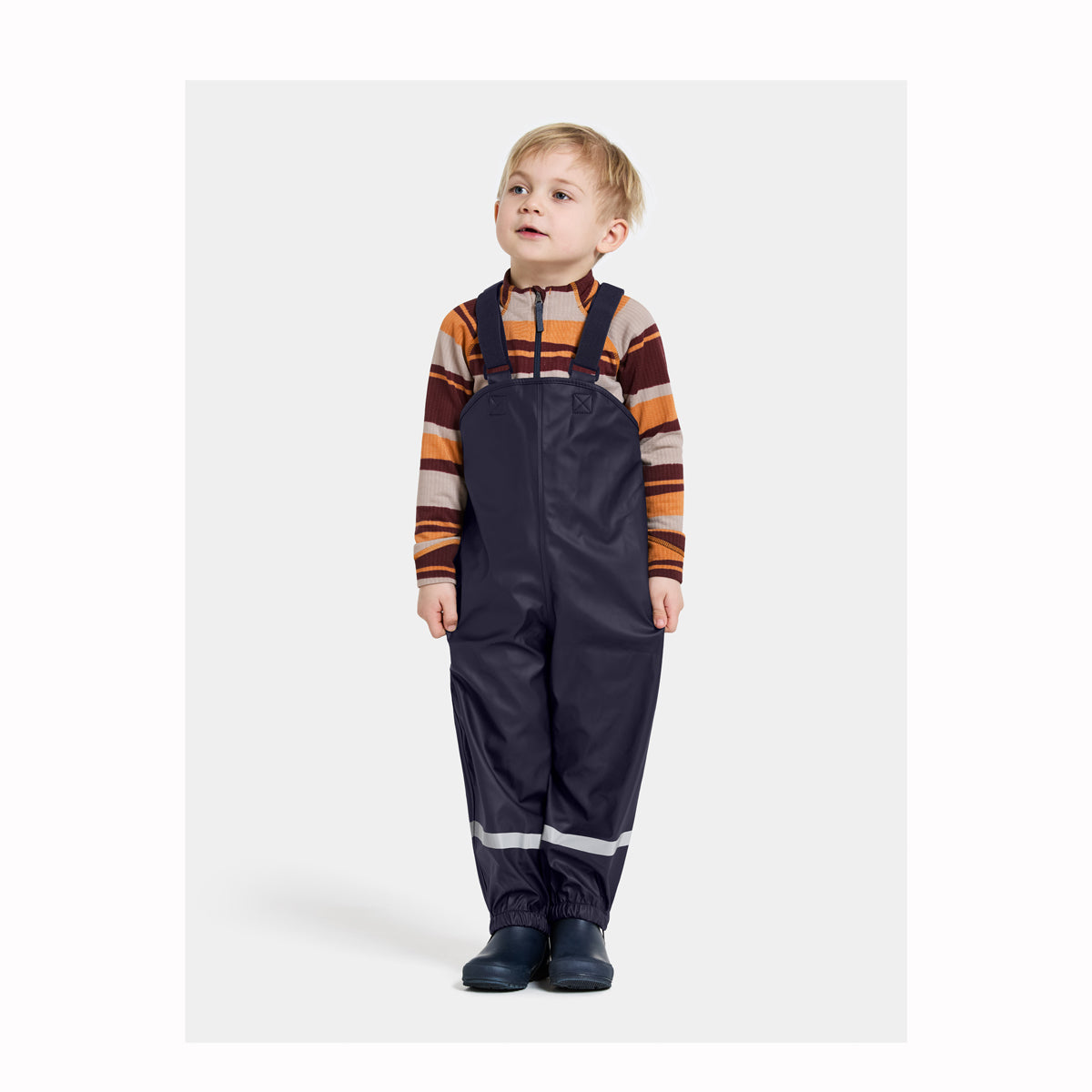Child wearing a striped shirt and dark overalls on a white background