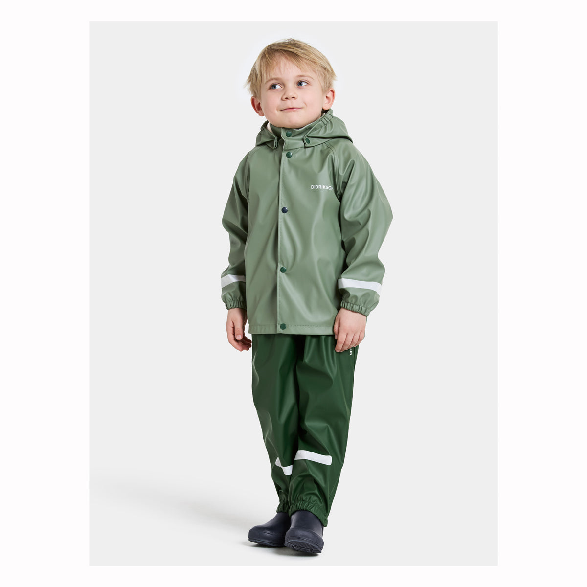 Child wearing a green raincoat and pants on a white background